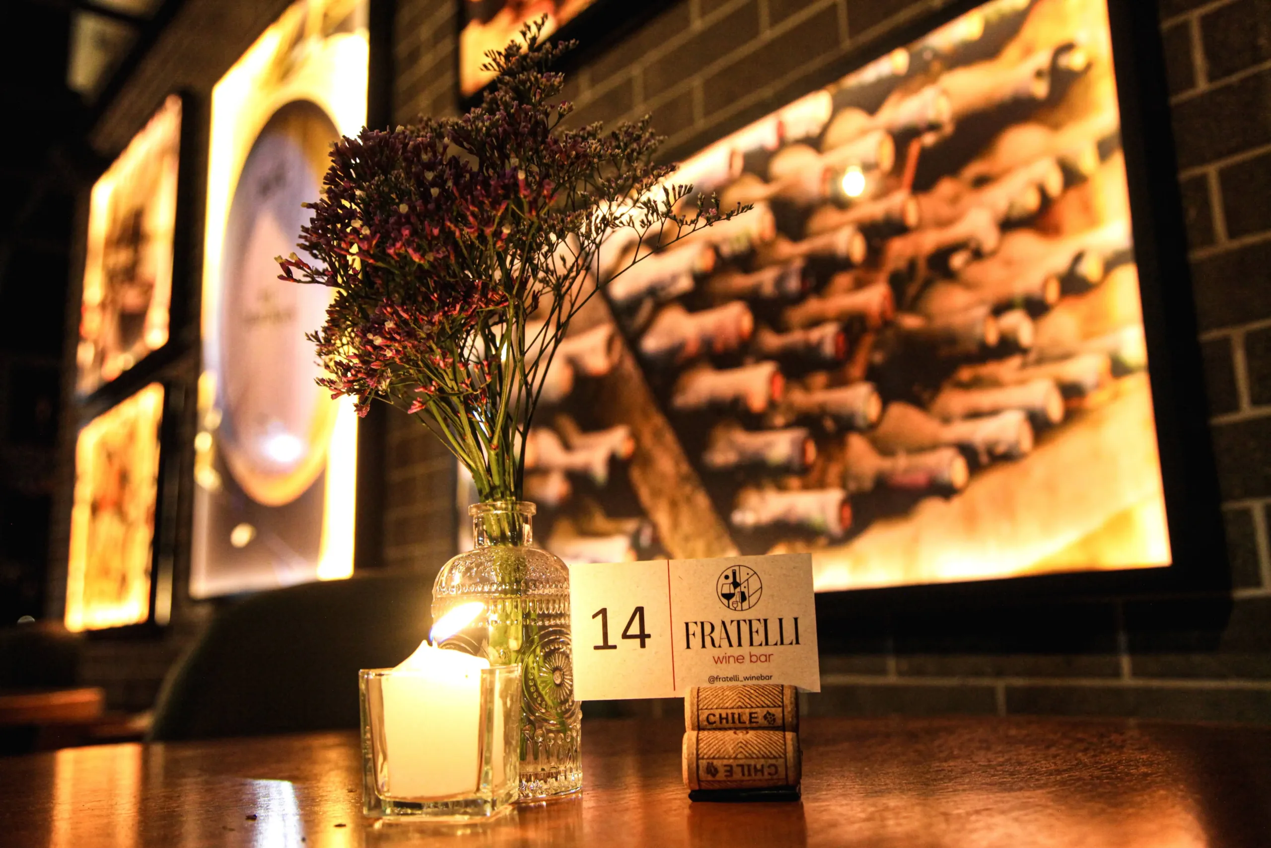 Detalhe decorativo de mesa com vela e flores no Fratelli Wine Bar