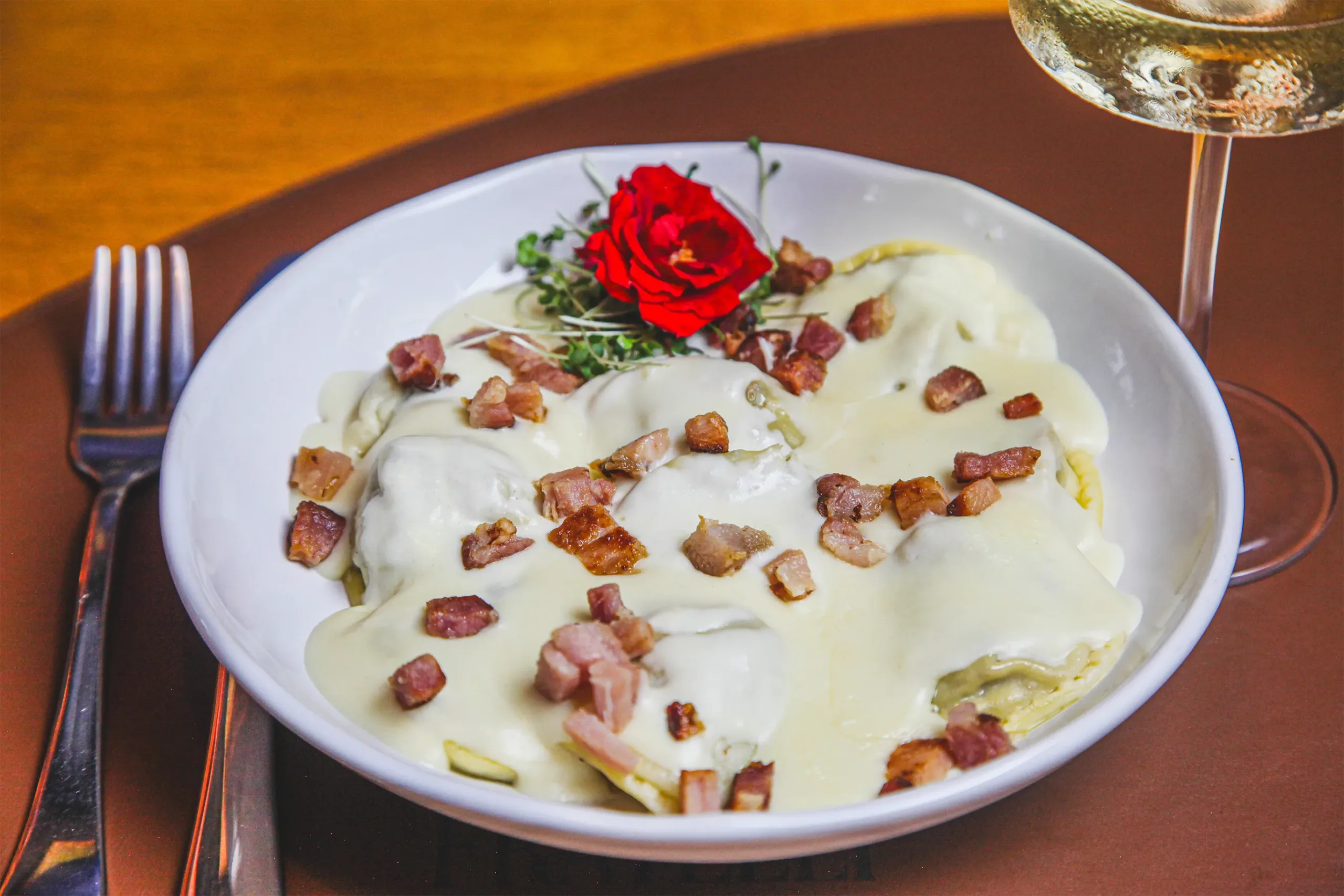 Massa recheada ao molho branco com bacon crocante no Fratelli Wine Bar, servida com vinho branco