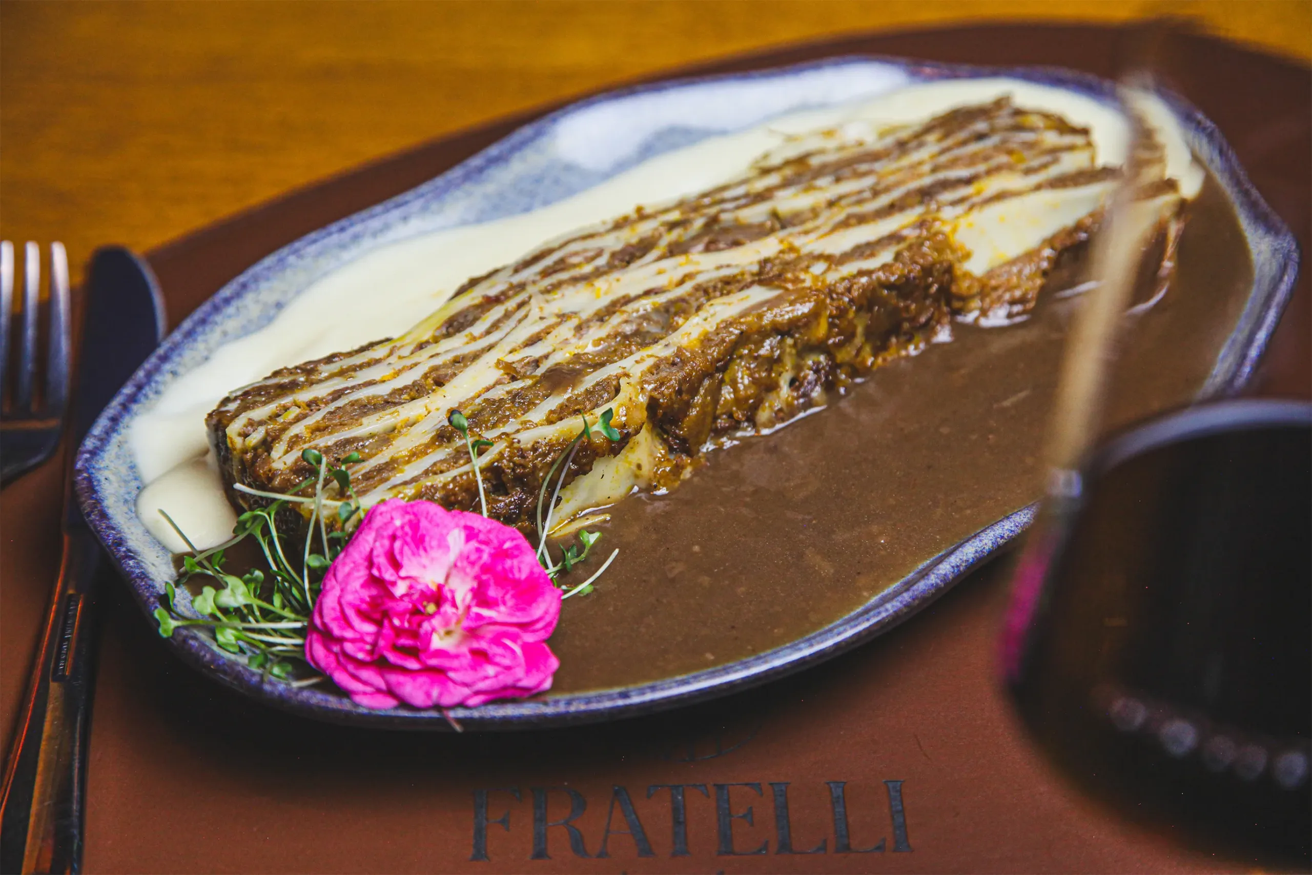 Lasanha artesanal ao molho servida no Fratelli Wine Bar com vinho tinto