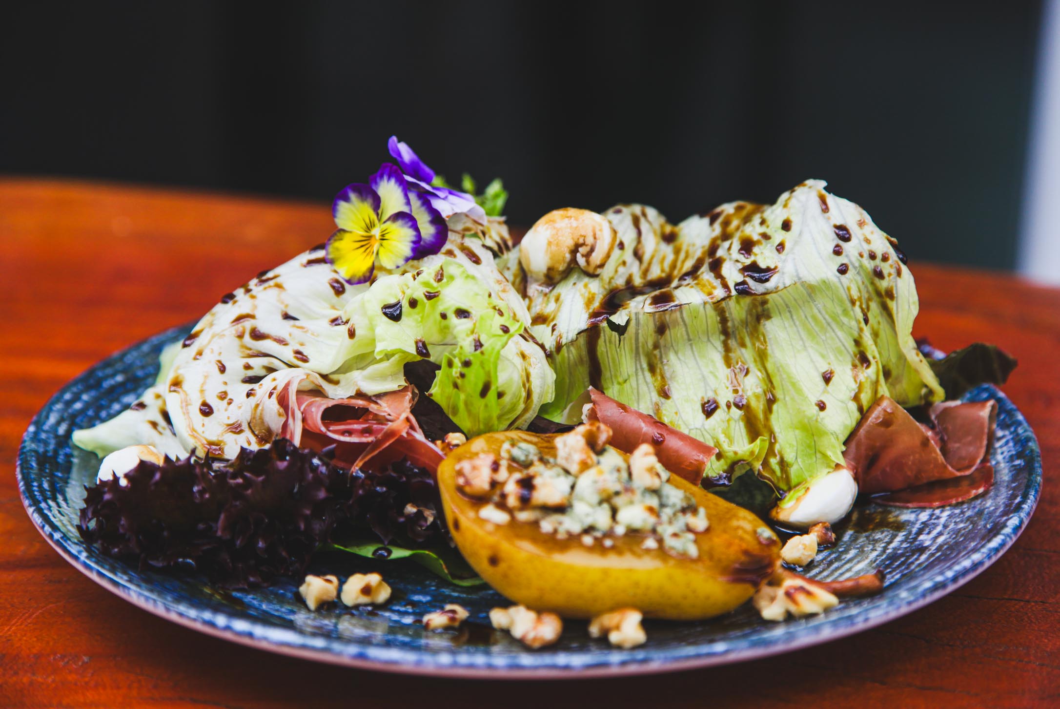 Salada gourmet com pera, gorgonzola, presunto cru, folhas frescas e flores comestíveis no Fratelli Wine Bar