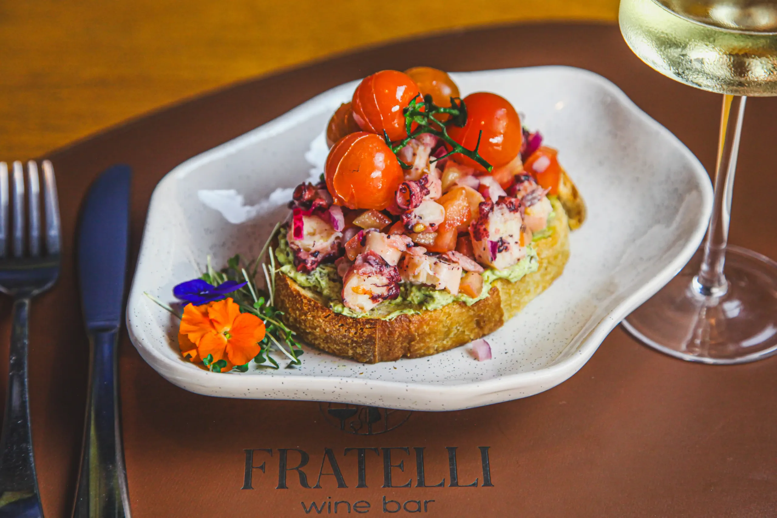 Bruschetta de polvo com creme de avocado e tomates confit servida com vinho branco no Fratelli Wine Bar em Holambra.