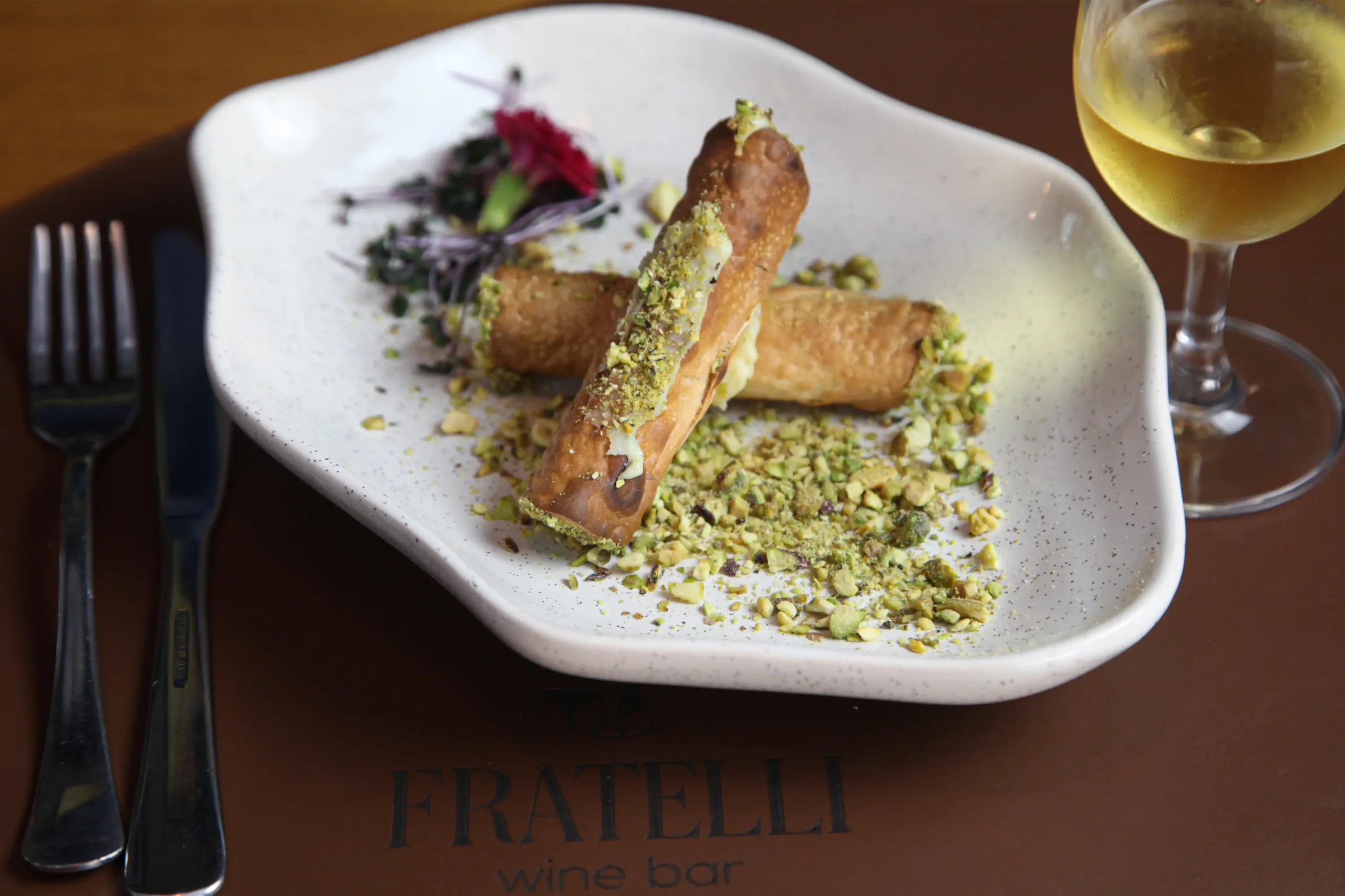 Cannoli italiano com creme doce e pistache servido com vinho branco no Fratelli Wine Bar em Holambra.