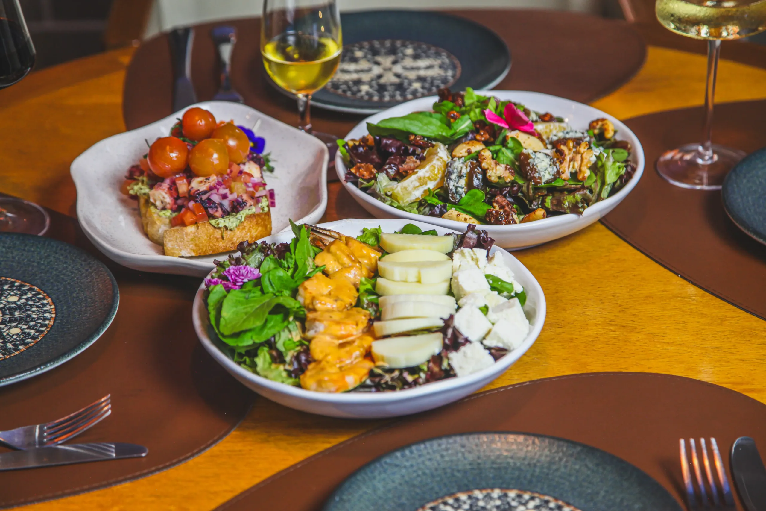 Bruschetta de polvo, salada com camarões e salada com gorgonzola e nozes, acompanhadas de vinho branco no Fratelli Wine Bar em Holambra.